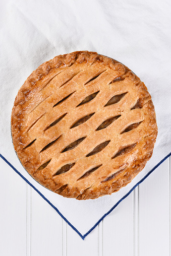 High angle view of a fresh baked apple pie on a white kitchen towel, Vertical format.