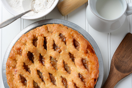 Fresh baked apple pie with a lattice crust. The pie is surrounded by baking items. Hogh angle. Horizontal format.