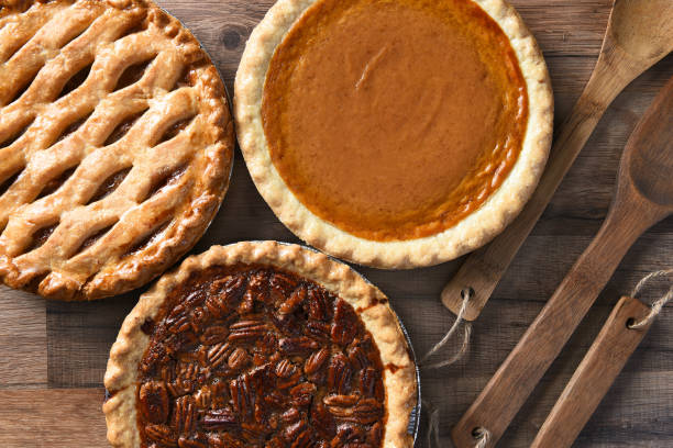 Pecan Apple and Pumpkin Pies Overhead view of three pies for a Thanksgiving Holiday feast. Pecan, Apple and Pumpkin in horizontal format on wood table savoury pie stock pictures, royalty-free photos & images