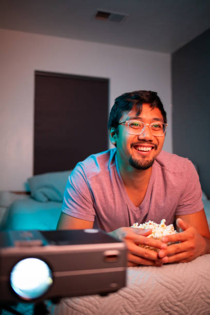 istock (Laughing) Man Watching a Movie in Bed with Projector 1411511747