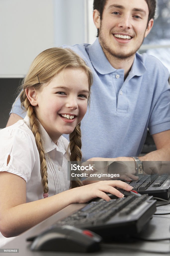 Professor ajudar a garota usando computadores em sala de aula - Foto de stock de Assistente royalty-free