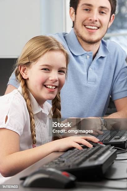 Foto de Professor Ajudar A Garota Usando Computadores Em Sala De Aula e mais fotos de stock de Assistente