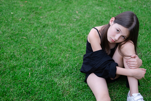 portrait of adorable teen brunette girl in black clothes outside. charming ukrainian child enjoying summer holidays vacation on green grass. pretty kids concept.