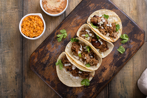 Pork carnitas tacos with onion and cilantro served with Mexican rice and refried beans