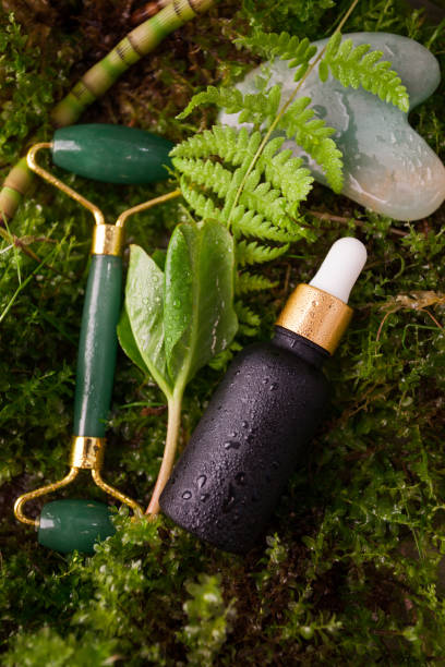 istock Green Jade roller, gua sha stone for face with serum, face oil on natural forest background. Facial massage set. The concept of Organic natural cosmetics, beauty, anti-age, banner for salon 1411525821