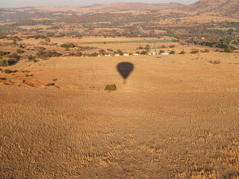 Shadow of balloon moving over big wide flat African landscape from hot air balloon in South Africa.