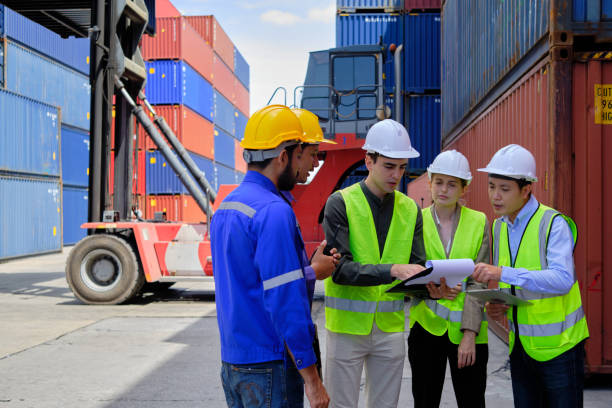 istock Group of workers teamwork at logistics terminal with many stacks of containers. 1411536005