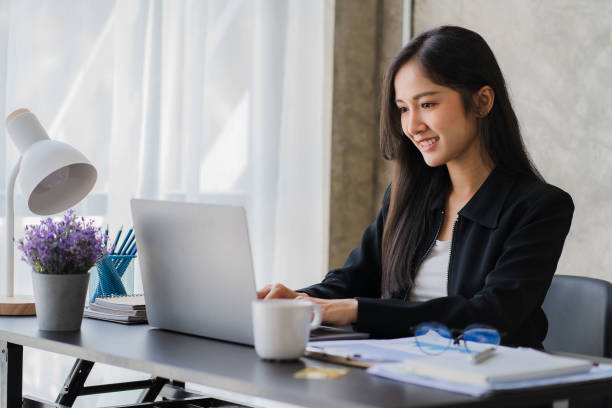 istock Happy Asian businesswoman using laptop computer while doing financial work. Successful with financial documents on the table 1411539068