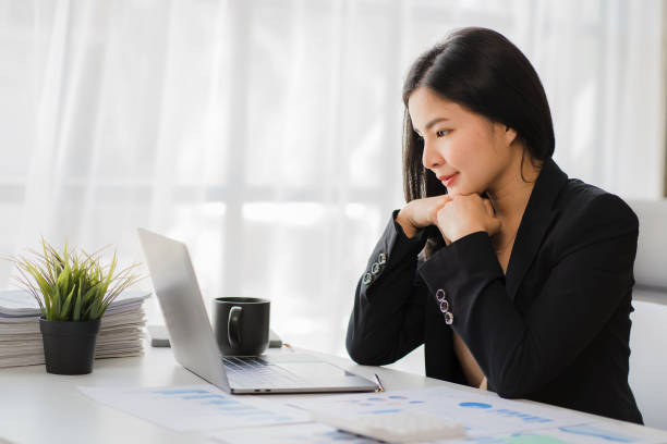 istock Happy Asian businesswoman using laptop computer while doing financial work. Successful with financial documents on the table 1411539076