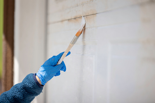 High quality stock photos of a grandson helping his grandmother repaint the garage door at her home.