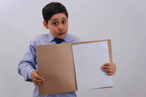 istock Boy dressed as a businessman with a shirt and a tie with an open folder with sheets that are blank to place any text. 1411543712