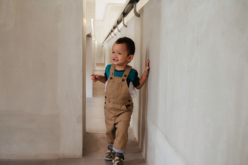 Cute child peeking through a corridor. Space for copy.
