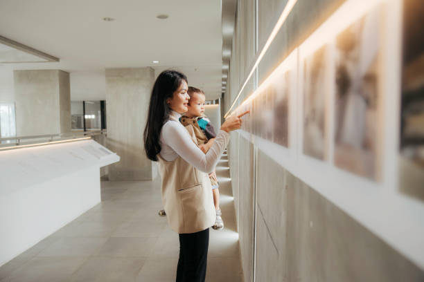 asiatische frauen schauen sich die ausstellung mit ihrem baby in der kunstgalerie an - version 2 fotos stock-fotos und bilder