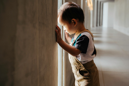 A young boy peering out a window