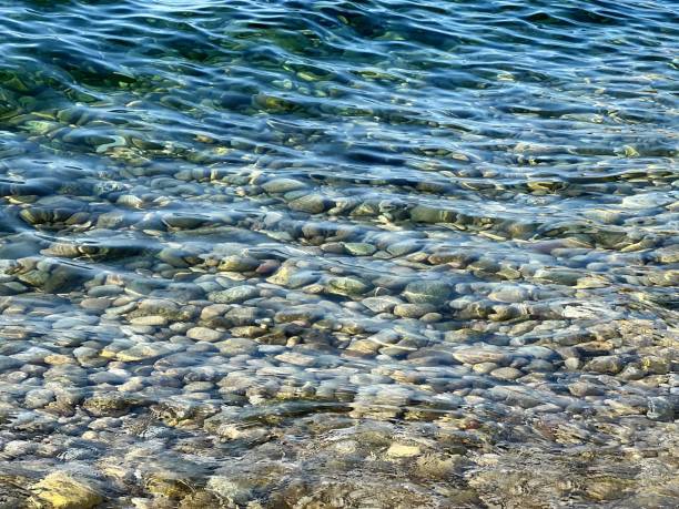 Pebbles under clear sea water waves. Smooth stones on the beach. Pebbles under clear sea water waves. Smooth stones on the beach. still water stock pictures, royalty-free photos & images