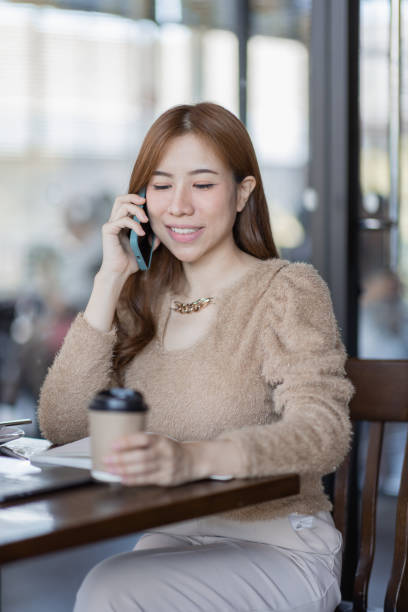 istock Asian businesswoman conversation on phone using a laptop while sitting in cafe 1411548523