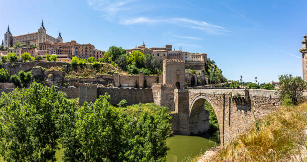The Alcantara bridge over the river Tagus. Toledo, Castilla La Mancha, Spain, View of Alcantara bridge over the river Tagus with the town Toledo on the other side of the bridge. The stone arch bridge was built over the Tagus River between 104 and 106 AD by an order of the Roman emperor Trajan. old town bridge tower stock pictures, royalty-free photos & images