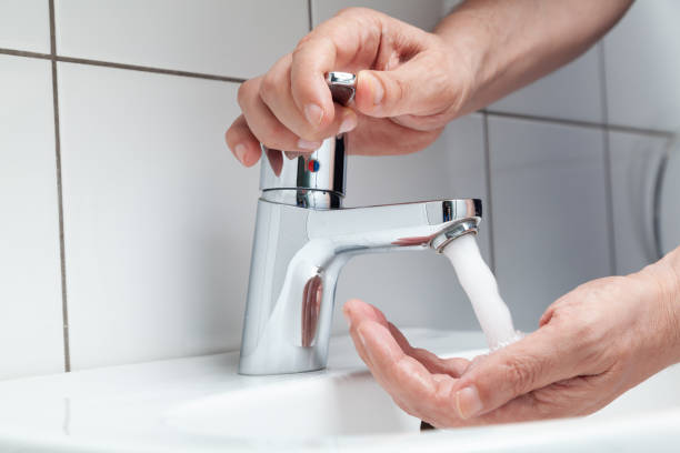 Man washes his hands in a white sink close-up stock photo