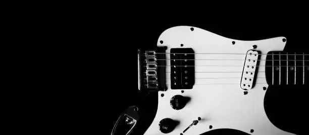 Photo of Part of body electric guitar on a black background, copy space. Black and white guitar close up. Creative photography, cropping. Concept music web blog, banner, poster, cover