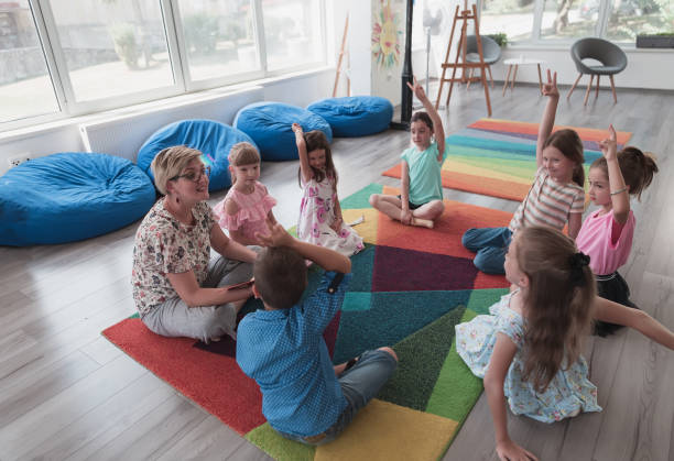 istock Reading time in elementary school or kindergarten, teacher reading a book to kids in elementary school or kindergaden. Selective focus 1411560119