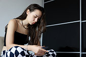 Pretty girl with long hair sitting with smartphone on sofa
