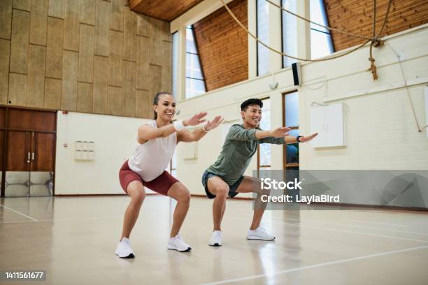 Two Athletes Squatting To Build Glutes And Build Strong Muscles During A Gym Fitness Workout Full Length Of Dedicated Fit And Active Friends Training In A Health Club Together Stock Photo - Download Image Now