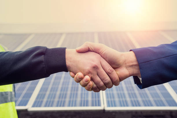 istock Workers in work clothes greet each other by the hand before starting work on solar panels. 1411565506