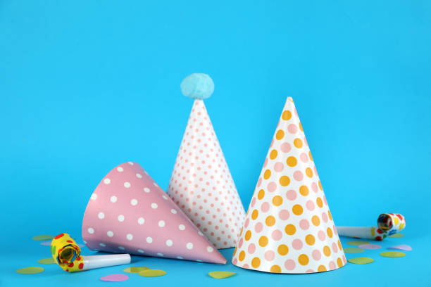 Bright party hats, horns and confetti on light blue background