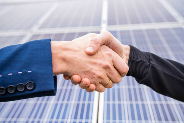 istock Workers in work clothes greet each other by the hand before starting work on solar panels. 1411567283