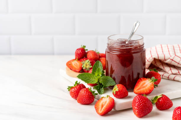 istock Strawberry jam in glass jar at white table. 1411568851