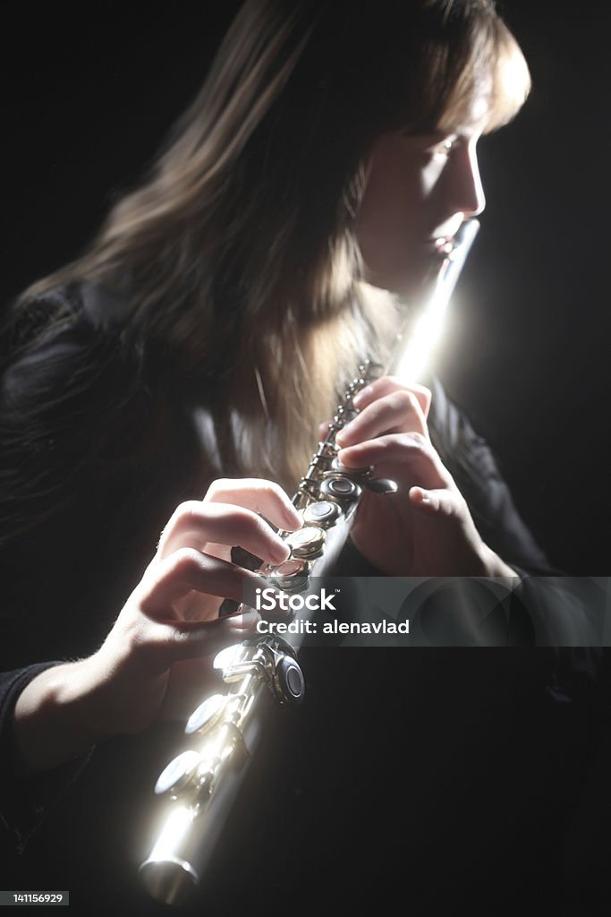 Flute playing flutist classical musician Flute playing flutist classical musician with bright musical instrument on the black background. Focus is on the right hand. Black Background Stock Photo