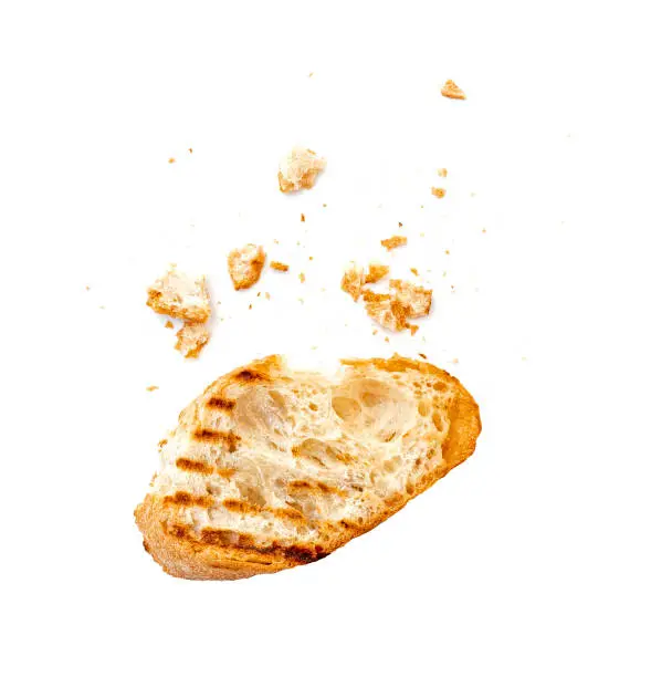 Piece of a dry white bread bruschetta or baguette with crumbs isolated on white