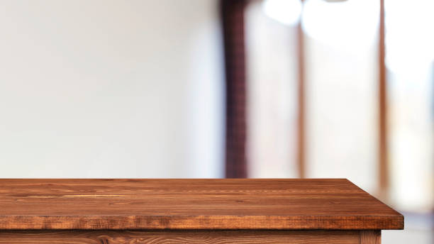 istock Brown empty wooden tabletop or table and blurred room interior with window and light 1411569796