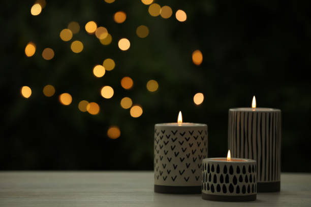 istock Burning candles on white wooden table outdoors, space for text. Bokeh effect 1411572079