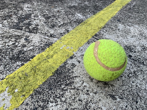 A tennis ball near a yellow line