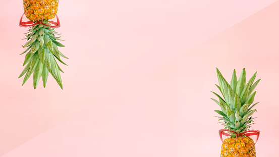 Creative layout made of pineapples with pink glasses on bright pink background. Original pineapple decoration. Minimal summer concept. Welcome summer.