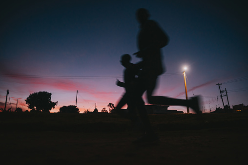 Morning run in Kenya. Kenyans and Africans tend to train early in the morning before sunrise. Silhouettes of runners with the color of dusk in the background