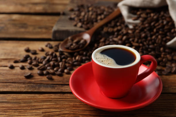 istock Cup of aromatic coffee and beans on wooden table. Space for text 1411574304