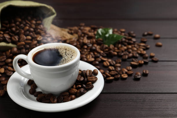 istock Cup of aromatic coffee and beans on wooden table. Space for text 1411574305
