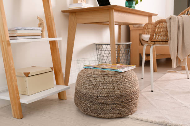istock Stylish knitted pouf with magazines on floor in modern home office. Interior design 1411575594
