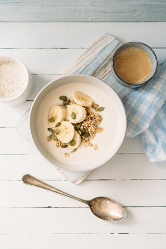 Curd cheese with granola, banana and pumpkin seeds in a bowl
