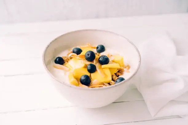 Curd cheese with granola, mango and blueberries in a bowl