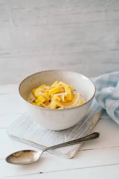 Curd cheese with granola, mango and toasted coconut in a bowl