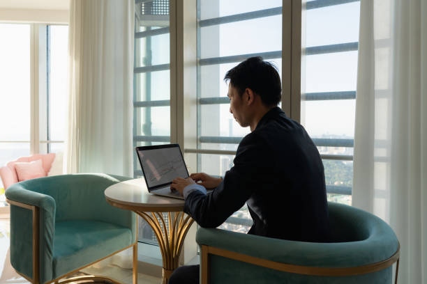 istock Male white collar sitting by the window and working with laptop 1411578664