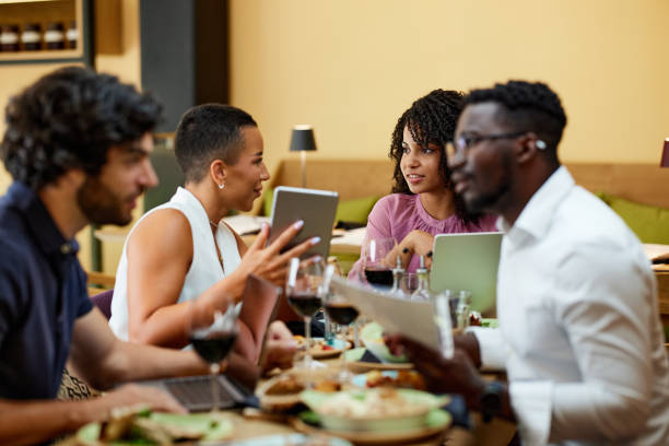 istock Busy businesspeople sit at the dinner table in a restaurant, working on laptops and having an important meeting. 1411579733