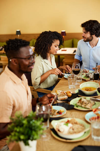 istock A group of multicultural friends eats dinner at the restaurant. 1411580755