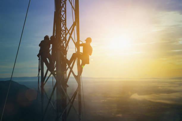 silhouette electricista trabaja en el concepto de industria pesada de terreno alto. construcción de la extensión de alta tensión en estaciones de alta tensión de forma segura y sistemática sobre fondo natural borroso. - torres de telecomunicaciones fotografías e imágenes de stock