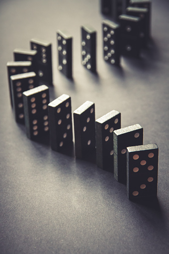 Black dominoes chain on a table background. Domino effect concept