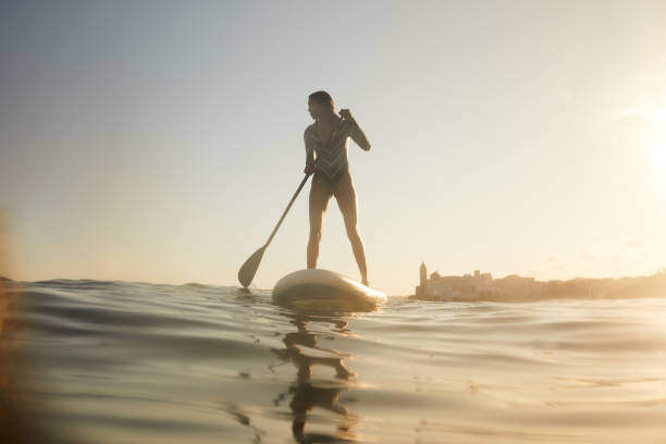 istock A woman is standing on a paddle surfboard. 1411581605