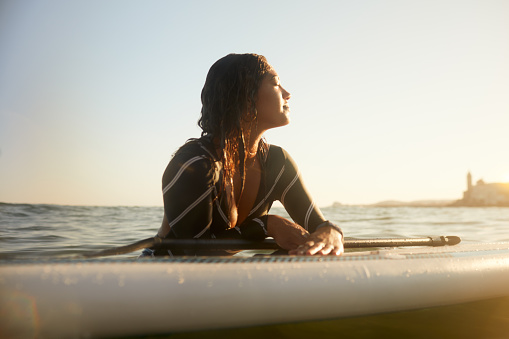 A woman is resting on a floating Paddle surfboard.